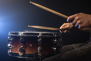 Close-up, snare drum on dark background with stage spotlight.
