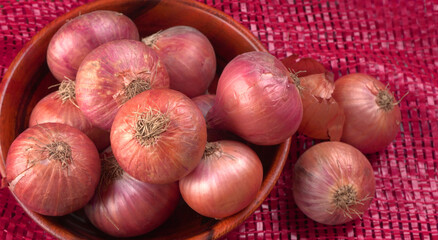 Fresh red onions in a wooden bowl.