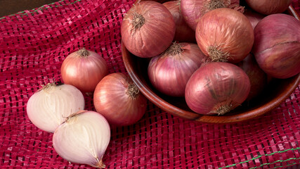 Fresh red onions in a wooden bowl.