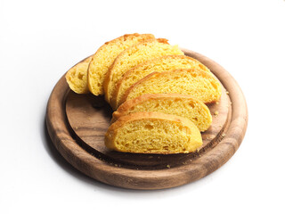 Slice of yellow pumpkin bread roll on round wooden board on white background