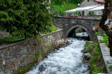 Fototapeta premium Rila Bulgaria, stream through mountain village with stone bridge