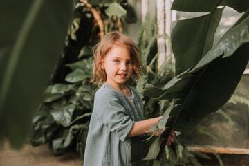 The face of a little girl surrounded by tropical leaves. A closeup portrait of a beautiful baby...