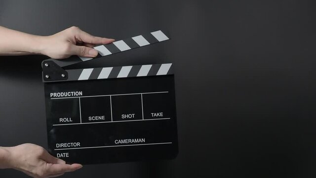Movie slate or clapperboard hitting. Close up hand holding empty film slate and clapping it on black background. Open and close film slate for video production. film production. Movie shooting.