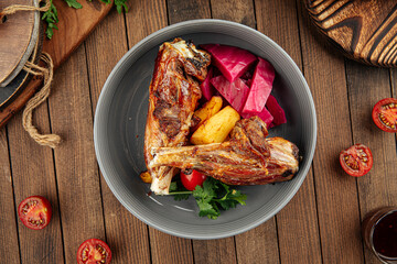 Gourmet prepared lamb legs dish with vegetables on wooden background