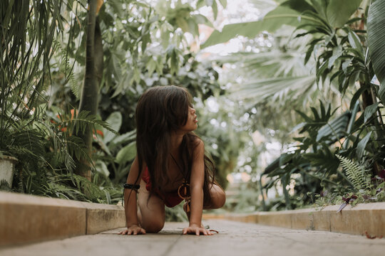 Mowgli indian little girl in a loincloth hides hiding in tropics green forest background. High quality photo