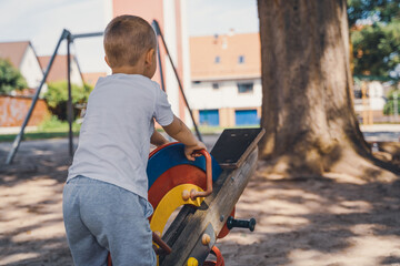 Boy playing alone on a colorful seesaw in the playground