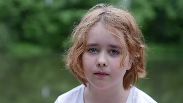 Close-up portrait of a sad teenage girl standing on the street during the day. The concept of the lonely life of a street child