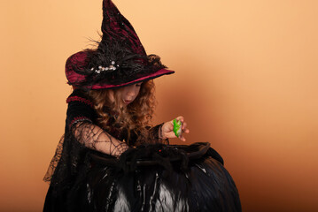 a brunette girl in a witch costume holding a frog conjuring over her in a witch's hat for Halloween