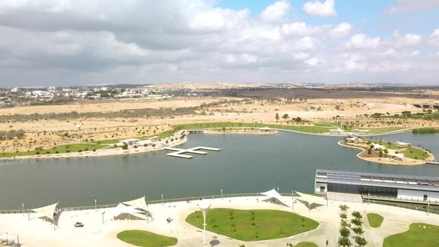 A golf cart moves along the shore of an artificial lake in the park in Beer Sheva