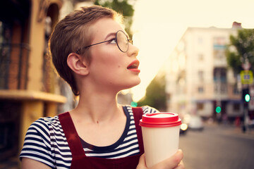 short haired woman wearing glasses outdoors walk leisure drink cup