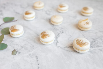 Tasty macarons on color background. Vanilla macarons with gilding on a marble table