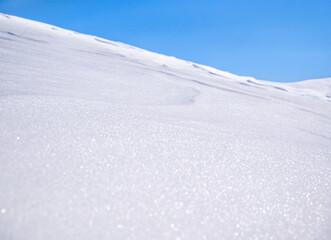 Detail with a mountain covered in white snow against clear blue sky.