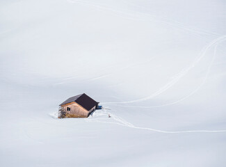 Aerial view with an abandon hut or cabin in the mountains in the middle of a sea of white fresh snow