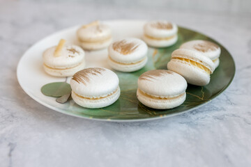 White macaroons are on a plate. Delicious light cookies on a plate on a light background. Bakery