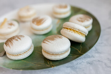 White macaroons are on a plate. Delicious light cookies on a plate on a light background. Bakery