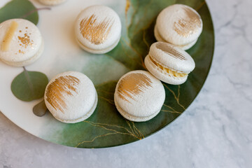 White macaroons are on a plate. Delicious light cookies on a plate on a light background. Bakery