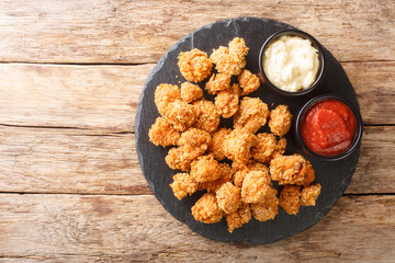 Crispy Chicken Popcorn with Tomato Ketchup and mayonnaise closeup in the slate dish on the table....
