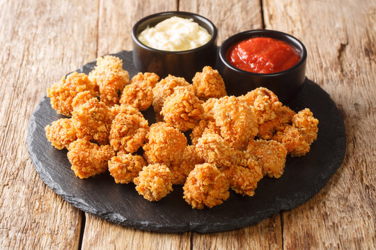 Chicken Popcorn are small slices of chicken that were coated breading and deep fried closeup in the slate dish on the table. Horizontal