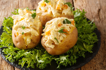Homemade hot baked potatoes stuffed with coronation chicken salad closeup in the slate dish on the table. Horizontal