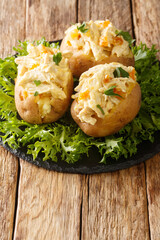 Baked potatoes stuffed with coronation chicken salad close-up on a slate board on the table....