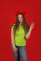 a young beautiful girl with long hair with a red bow on her head in a light green T-shirt in blue...
