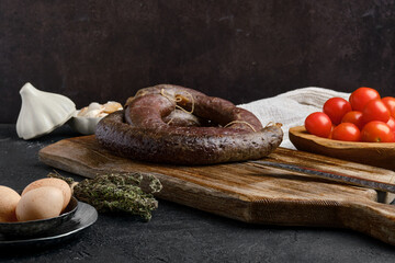 Blood sausage rolled on wooden cutting board.
