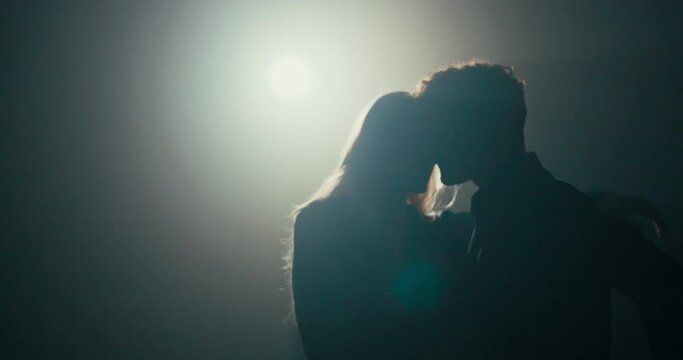 Elegant couple in love spend time dancing alone handsome man in black shirt holds hands with partner beautiful woman with long blonde hair darkness lit by one lamp romantic atmosphere