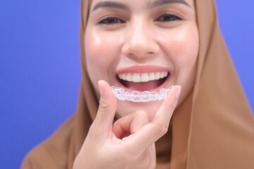 Young muslim woman holding invisalign braces in studio, dental healthcare and Orthodontic concept..