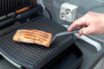 The chef prepares trout on an electric grill. Healthy food. Chef's hand. Homemade food. Photo