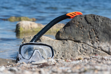 Scuba mask and diving snorkel on the sea shore background.