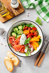 Salmon bowl with spinach,arugula, cherry tomatoes, cucumber, orange slices, radish and cream cheese. Homemade food. Concept for a tasty and healthy meal. Light gray stone background. Top view.