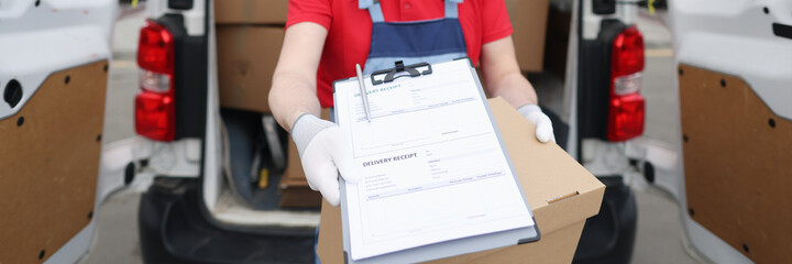Courier driver in medical protective mask and gloves holds out documents with delivery receipt