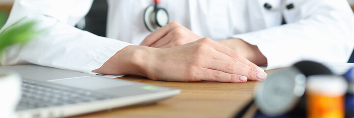 Hands of doctor in white coat at workplace
