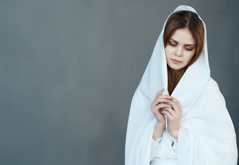 woman covers herself with white cloth charm dark background posing