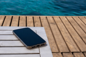 mobile phone standing on wooden floor by the beach