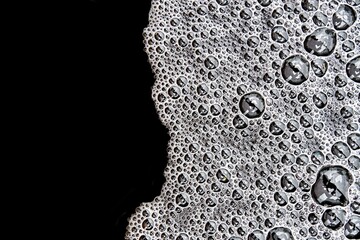 Gentle white foam with bubbles pattern on dark water surface after heavy rain as decorative...