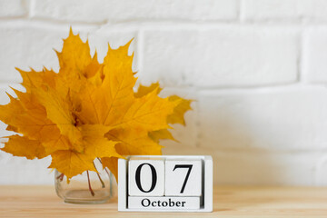 October 7 on the calendar and a bouquet of bright autumn leaves on the table.One of the days of the autumn month.Calendar for October. The concept of the golden autumn.