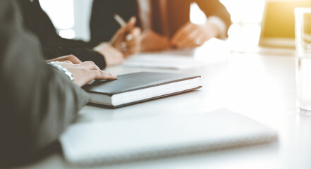 Unknown businessmen and woman sitting, working and discussing questions at meeting in sunny office, close-up. Success concept