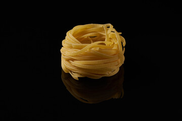 Closeup of raw rolled tagliatelle pasta isolated on black background