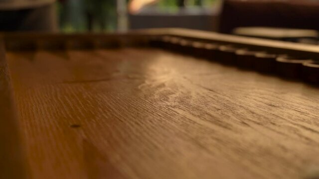 a man's hand throws colorful dice on a wooden backgammon board