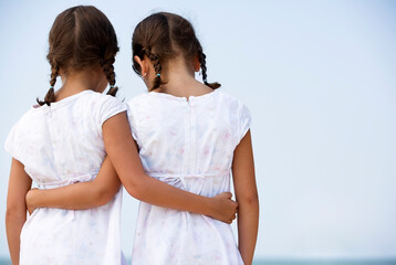 Fototapeta na wymiar Hispanic Sisters Wearing Matching Dresses and Hugging, Sad Child Girls