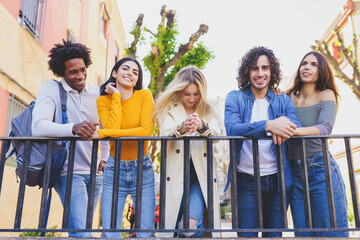 Multiracial group of young people talking together in the street.