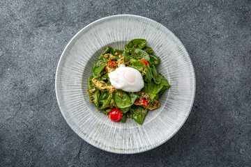 Salad with spinach, eggplant, tomatoes, poached eggs. Diet healthy nutritious food. Ready menu for the restaurant. Neutral gray blue textured background