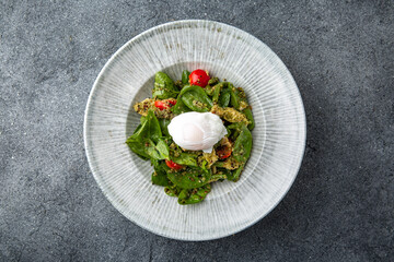 Salad with spinach, eggplant, tomatoes, poached eggs. Diet healthy nutritious food. Ready menu for the restaurant. Neutral gray blue textured background