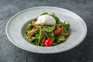 Salad with spinach, eggplant, tomatoes, poached eggs. Diet healthy nutritious food. Ready menu for the restaurant. Neutral gray blue textured background