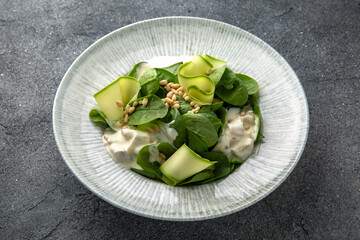 Hearty salad with mushrooms and chicken in a creamy sauce, zucchini and spinach with pine nuts. Diet food. Ready menu for the restaurant. Neutral gray blue textured background