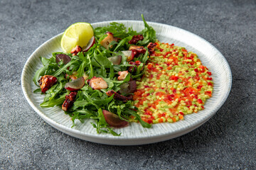 Grilled octopus salad, avocado, tomatoes, sweet peppers. Ready menu for the restaurant. Neutral gray blue textured background
