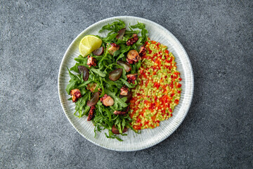 Grilled octopus salad, avocado, tomatoes, sweet peppers. Ready menu for the restaurant. Neutral gray blue textured background