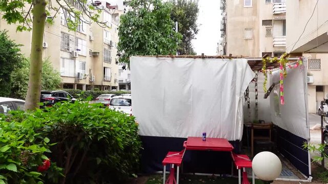 Jewish festival of Sukkot in Israel. Traditional sukkah with handmade decorations near the building on the street. 