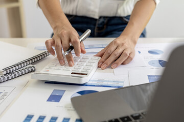 financial business woman pressing a white calculator, she uses a calculator to calculate the numbers in the company's financial documents that employees in the department create as meeting documents.